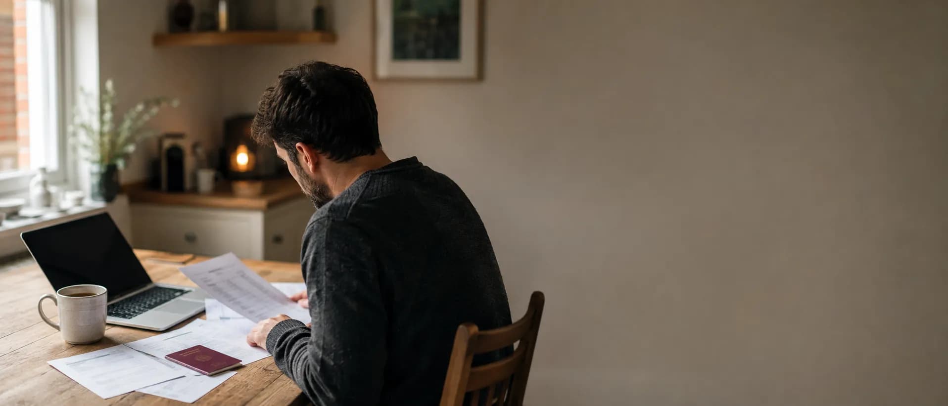 A Skilled Worker visa holder reviewing payslips and bank statements at a kitchen table before a mortgage application.